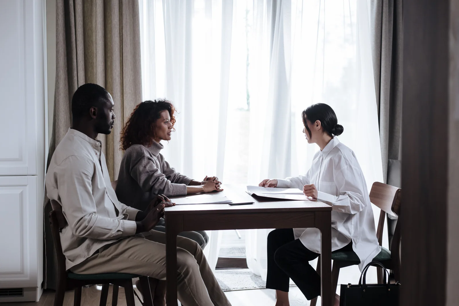 Three adults discussing paperwork together at a table